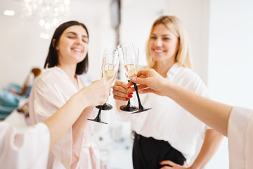 Group of girlfriends clink glasses in beauty salon