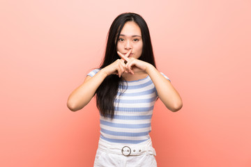 Teenager asian girl over isolated pink background showing a sign of silence gesture