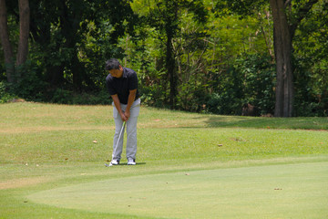 Obraz premium Golfer putting golf into the hole in beautiful golf course. The evening golf course with sunset in thailand