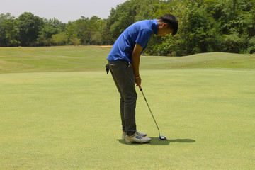 Golfer putting golf into the hole  in beautiful golf course. The evening golf course with sunset in thailand