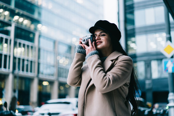Young woman in coat taking photo on camera