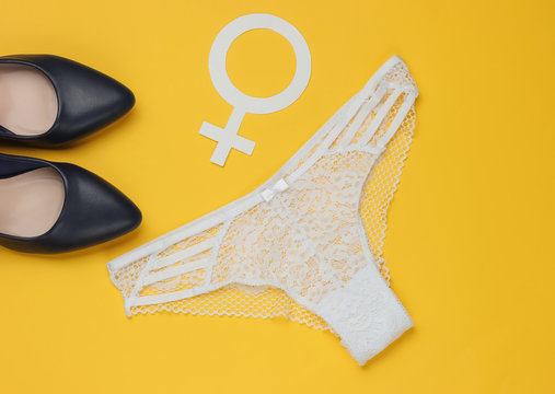Women's sexy lace panties, high heel shoes and gender Femen symbol on yellow background. The concept of feminism. Top view