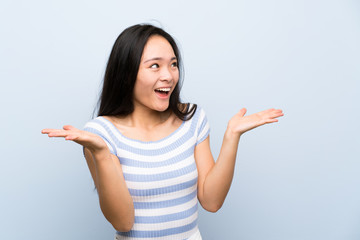 Teenager asian girl over isolated blue background with surprise facial expression