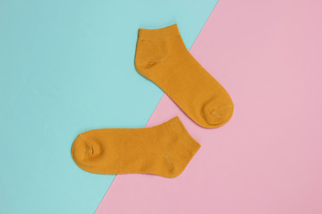 Orange socks on pink blue background. Pastel color trend. Top view