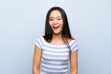 Fototapeta premium Teenager asian girl over isolated blue background with surprise facial expression