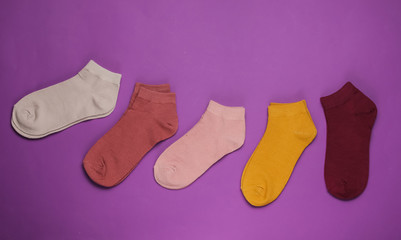 Set of colored socks on purple background. Top view