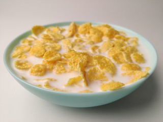 cornflakes with milk in a blue plate on a white background. Delicious healthy Breakfast.