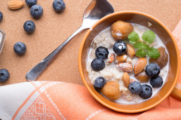 bowl of oatmeal porridge with blueberries, fruits,  almonds and coconut milk. Healthy and tasty vegan breakfast. top view, flat lay.