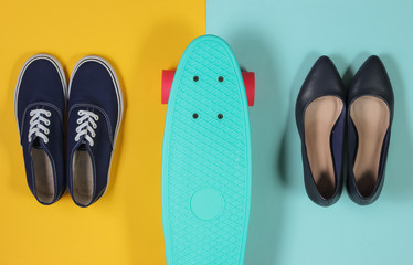 Cruiser board on blue-yellow background with sneakers and classic high-heeled shoes. Top view