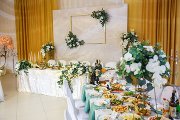 View of the served for decorated wedding dinner table in elite restaurant with beautiful flowers.