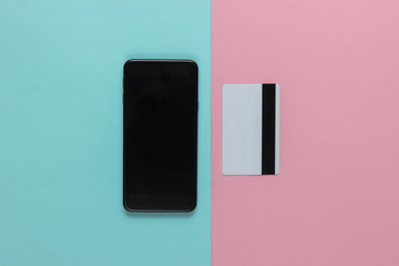 Smartphone and bank card on pink blue pastel background. Contactless payment. Online shopping. Top view. Minimalism