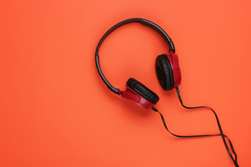 Modern wired headphones on orange background. Music lover concept. Top view