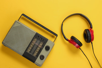FM radio receiver, retro style wired headphones on yellow background. Music lover concept. Top...