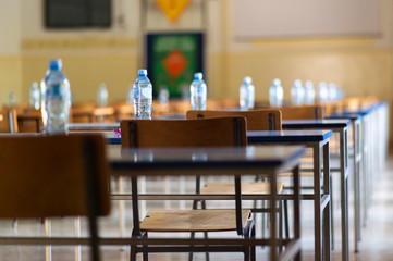 Exam examination room or hall set up ready for students to sit test. multiple desks tables and chairs. Education, school, student life concept.