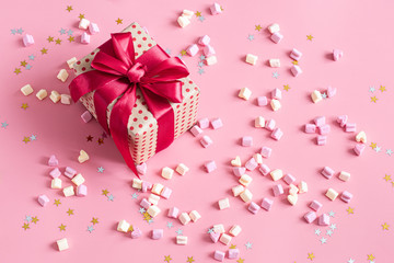 The concept of Valentine's day. Gift box with red bow on pink background.