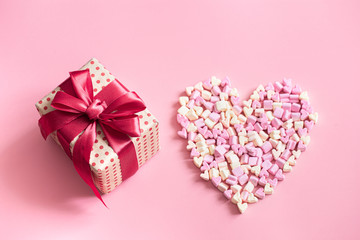The concept of Valentine's day. Gift box with red bow on pink background.