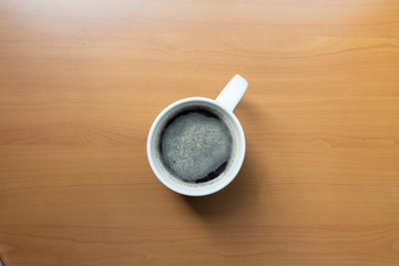 Cup of coffee on wooden table, top view