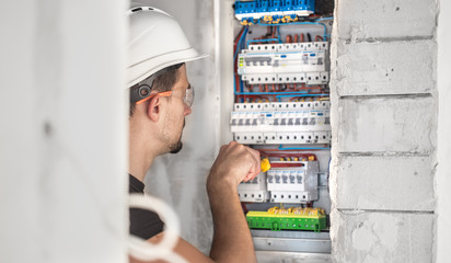 Man, an electrical technician working in a switchboard with fuses. Installation and connection of electrical equipment.