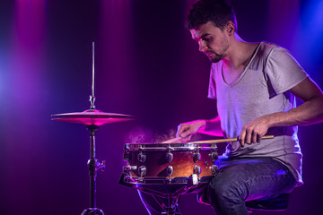 The drummer plays the drums. Beautiful blue and red background, with rays of light. Beautiful...