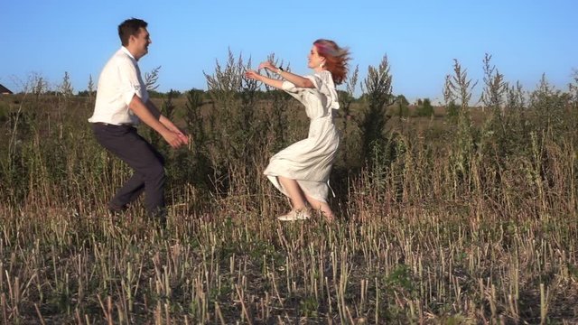 Romantic young couple story a girl jumps into the hands of a guy. Woman is running to her man, they hug and spin around on a outdoor. Theme of love and happiness of family. Slow motion at 250 fps.