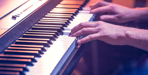 male hands on the piano keys closeup of a beautiful colorful background © puhimec