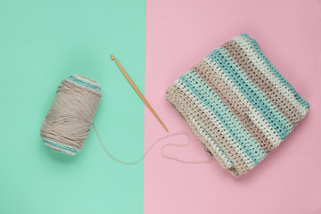 Yarn with skeins of woolen threads and a wooden crochet for knitting on a blue-pink pastel...