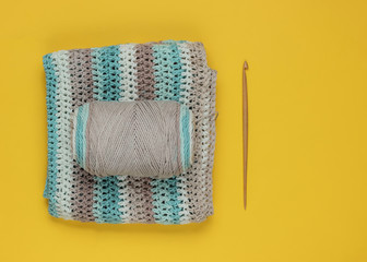 Yarn with skeins of woolen threads and wooden crochet for knitting on yellow background. Top view