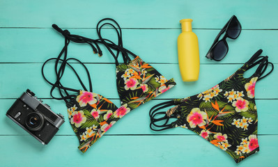 Summer fun background. Woman's swimsuit and beach accessories on blue wooden background. Overhead view of woman's swimwear. Vacation on the beach. Flat lay, top view.