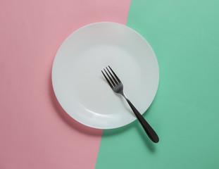 Empty plate with a fork on pink blue pastel background. Studio shot. Restaurant food concept.