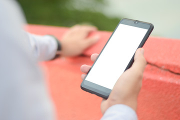 close up hand holding smart phone and white screen outdoor over blured background, mobile phone concept.