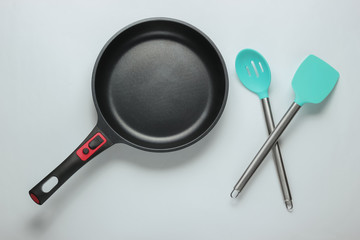 Non-stick pan with cooking spatula on white background. Cooking minimalism concept. Studio shot. Top view