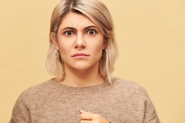 Portrait of stylish moody angry young Caucasian woman wearing facial piercing and warm sweater...