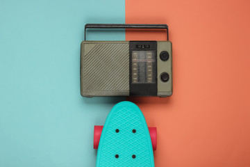Overhead view of cruiser board, radio receiver on a blue-pink pastel background. Summer fun, 80s...