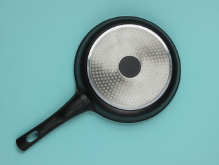 The bottom of the non-stick pan. Inverted empty pan upside down on blue background. Top view