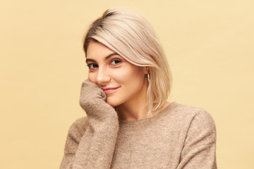 Isolated shot of adorable young European female with dyed bob hairstyle looking at camera with...