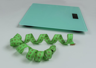 Floor scales, measuring tape on white background. The concept of losing weight. Studio shot. Top...