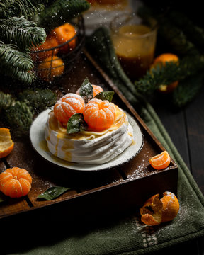 Tangerine Pavlova. Famous Delicious Dessert Of Meringue, Cream And Fruit. Christmas Look With Tangerines On The Background Of The Christmas Tree