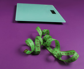 Floor scales, measuring tape on white background. The concept of losing weight. Studio shot. Top...