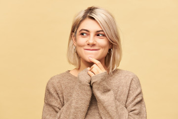 Beautiful mysterious European girl in stylish cozy sweater having amazed enigmatic facial...