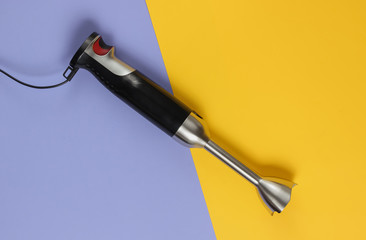 Electric hand blender on a purple-yellow background. Top view