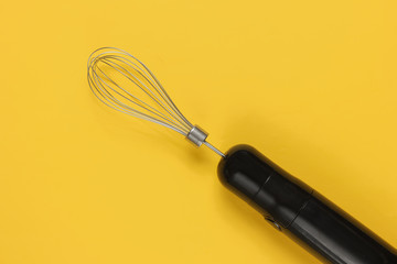 Electric hand whisk blender on yellow background. Top view