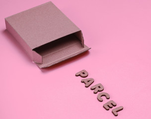 Postal services minimal concept. Empty cardboard box on pink paper background with a slogan parcel