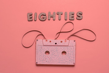 Creative retro style concept, 80s. Audio cassette on pink background with the word Eighties from...