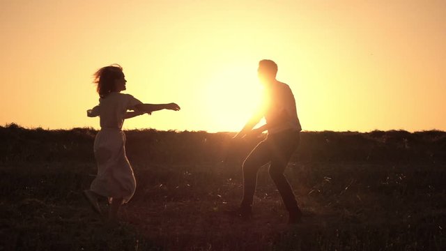 Romantic couple spinning hugging on sunset background. Woman is running to her man, they hug and spin around on a outdoor. Theme of love and happiness of family. Slow motion at 250 fps.