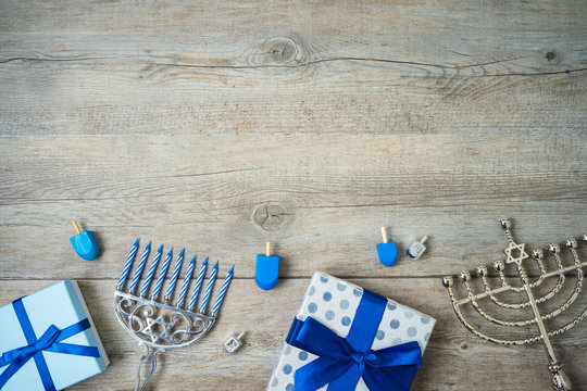 Jewish holiday Hanukkah background with menorah, gift boxes and dreidel on wooden table.