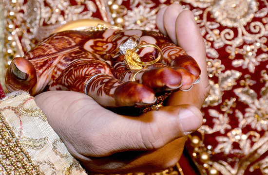 An Indian bride and groom holding their hands with ring during a Hindu wedding ritual