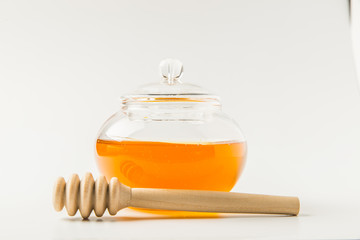 Glass jar of honey with honey dipper isolated on a white background with space for text 