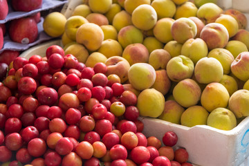 Plum and peaches stacked in the sale of a food market in Colombia.