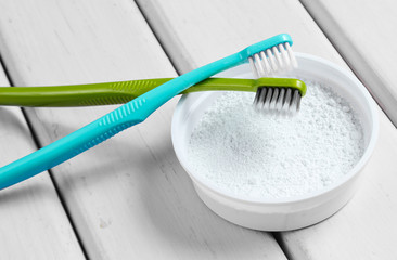 Two toothbrushes, tooth powder on white wooden background. Minimalism oral hygiene concept. Top view