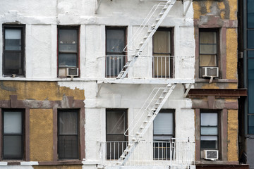 Fototapeta na wymiar Half-painted New York Building with Fire Escapes. A typical New York City apartment building gets a facelift with some new white paint but the job is only half done..